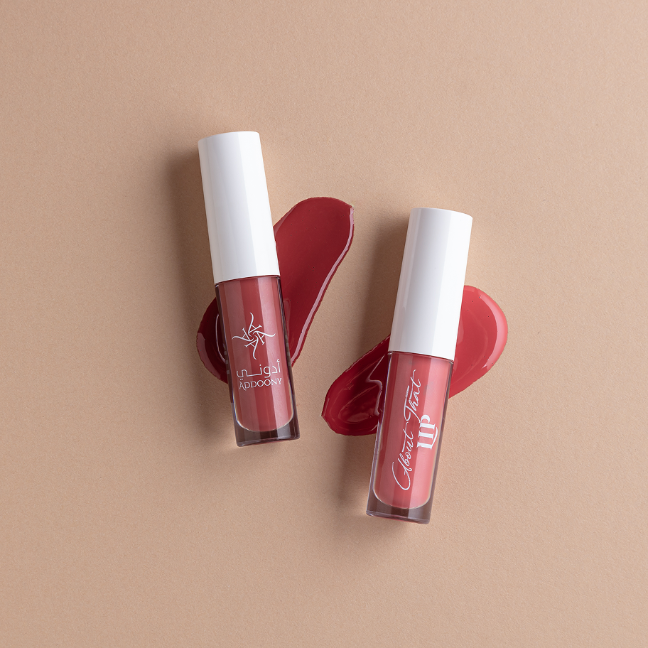 Two lip glosses with white caps on a beige background