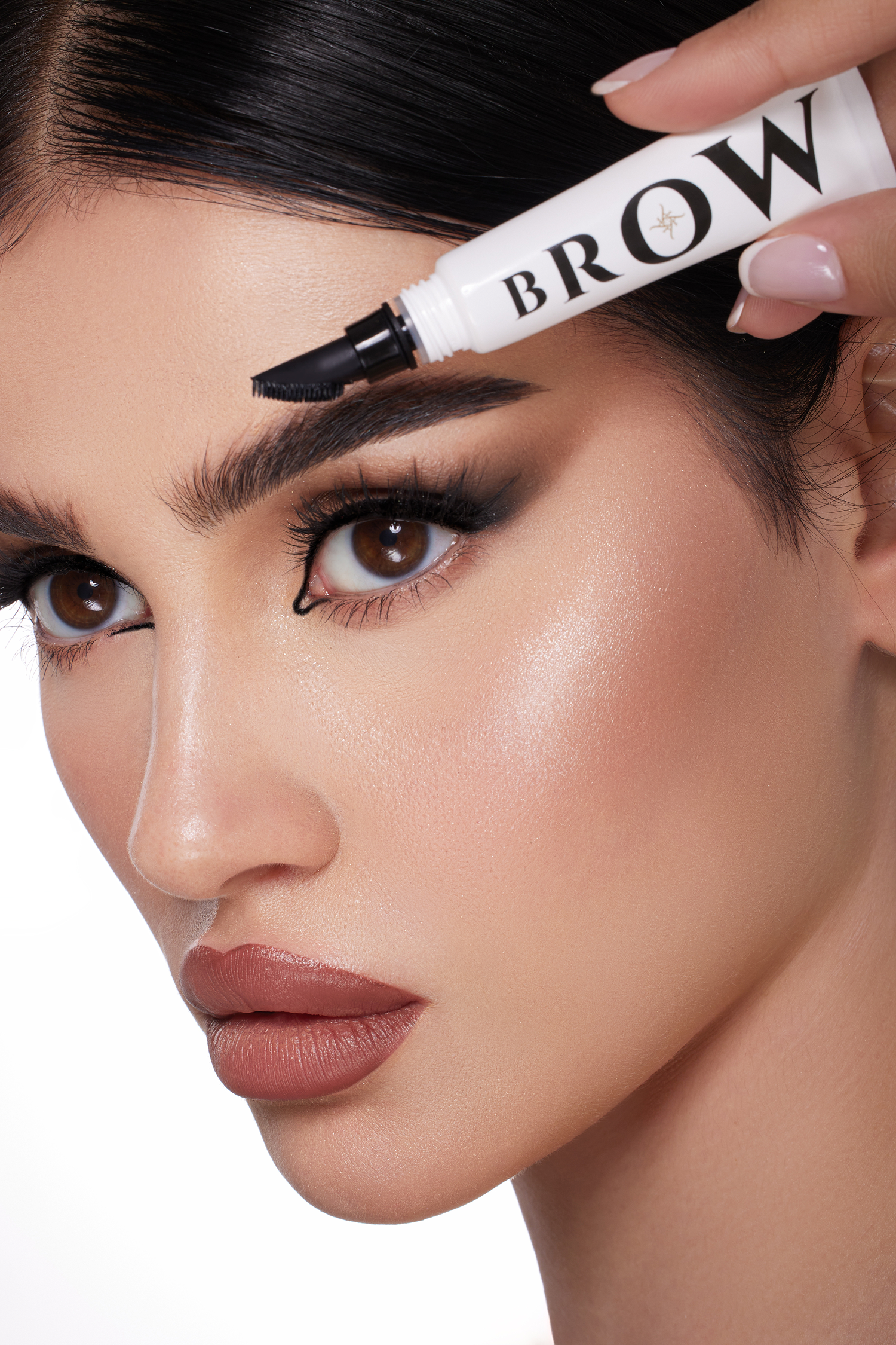 Woman applying brow product to her eyebrows with a marker labeled 'Brow'.