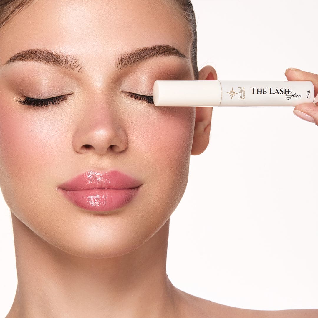 Woman applying eyelash gel to her eye with a clear background