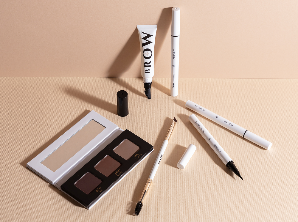 Eyebrow makeup set with palette, pencils, and serum on a beige background