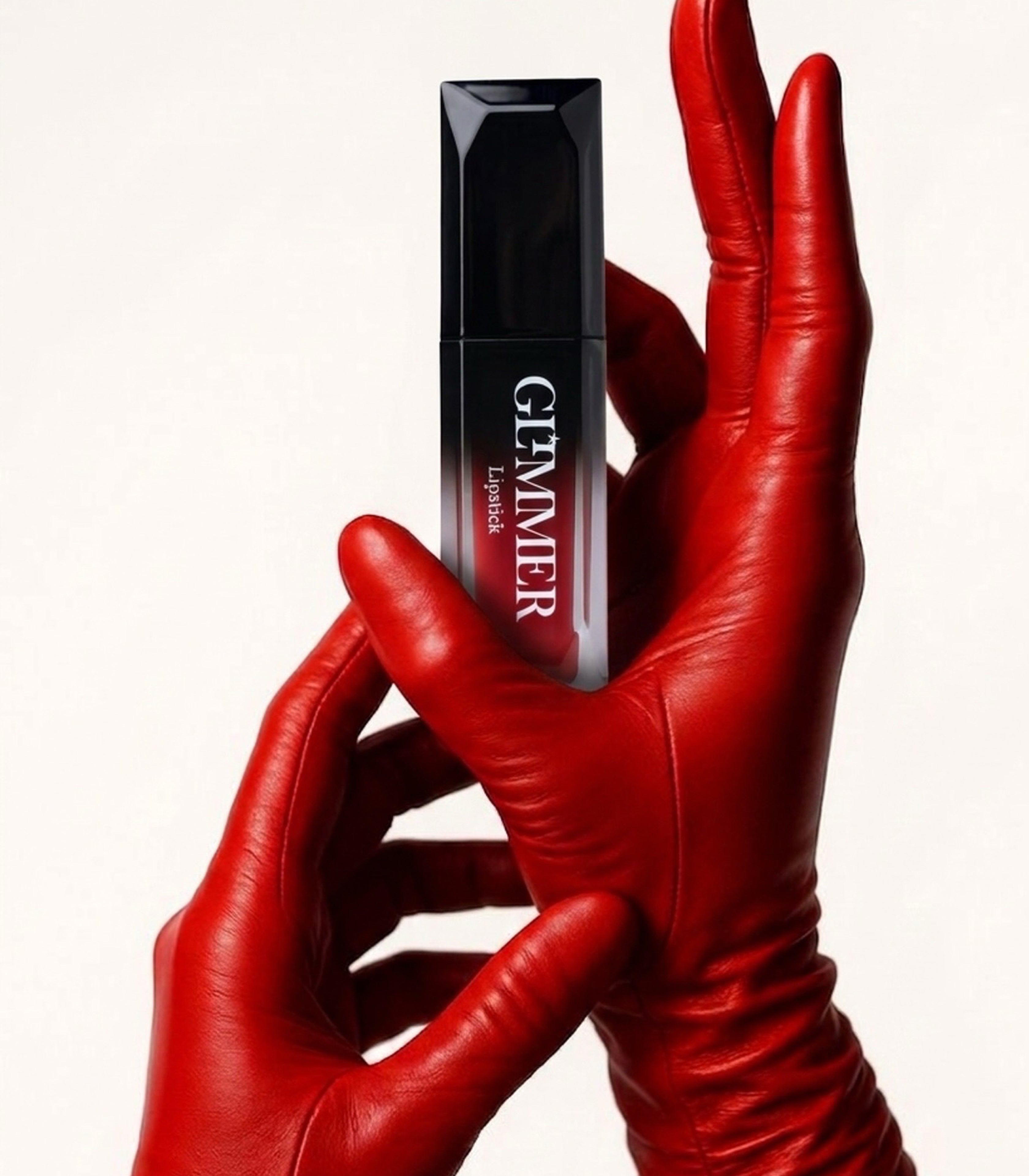 A pair of hands wearing glossy red gloves holds a black rectangular cosmetic tube labeled GEMNER Lipgloss against a clean white background.