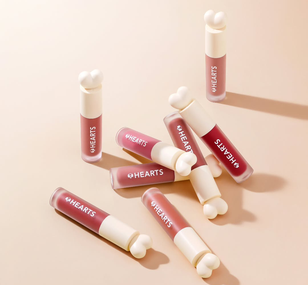 Lip gloss tubes with 'hearts' branding on a beige background
